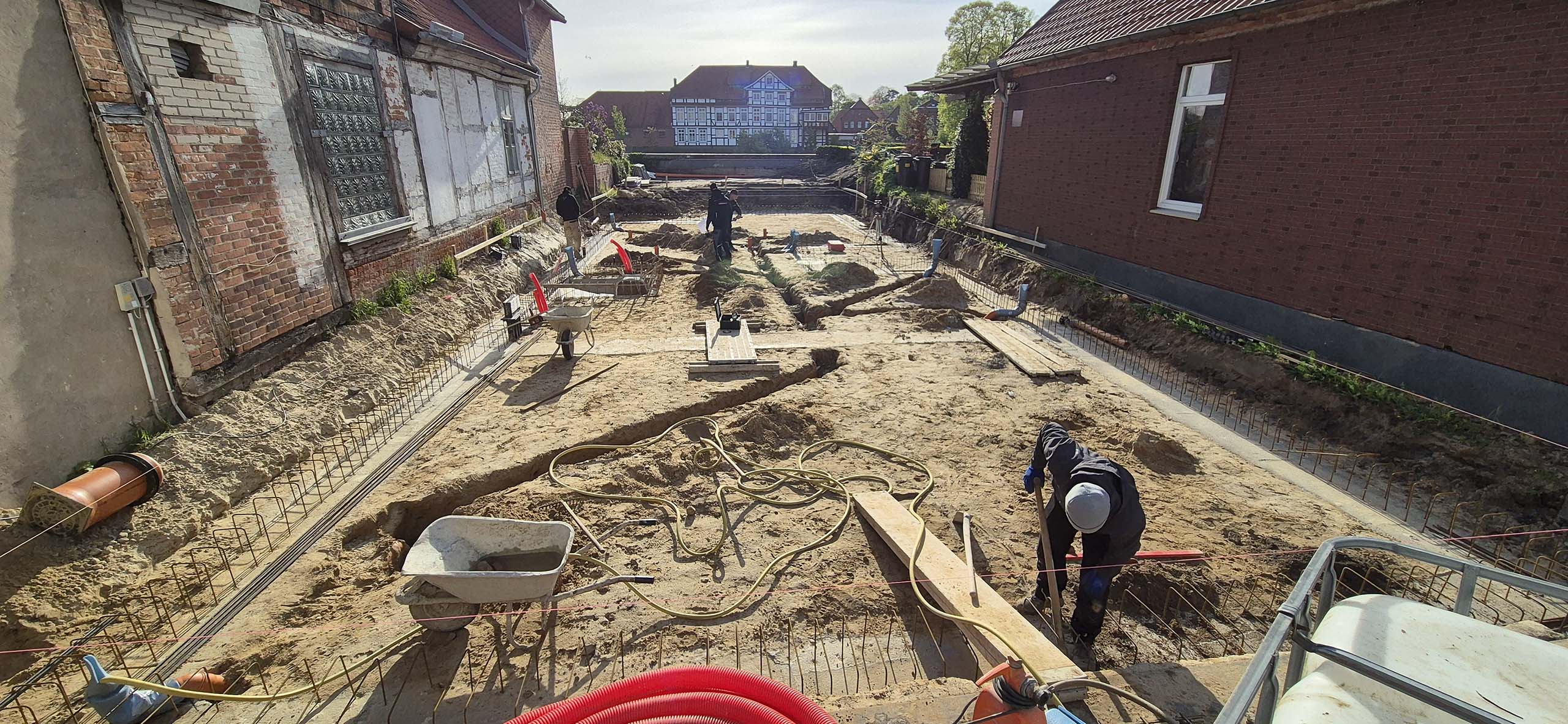 Bauprojekt in Hoya. Drei Bauarbeiter bereiten das Fundament und die Verlegung der Abflüsse vor.