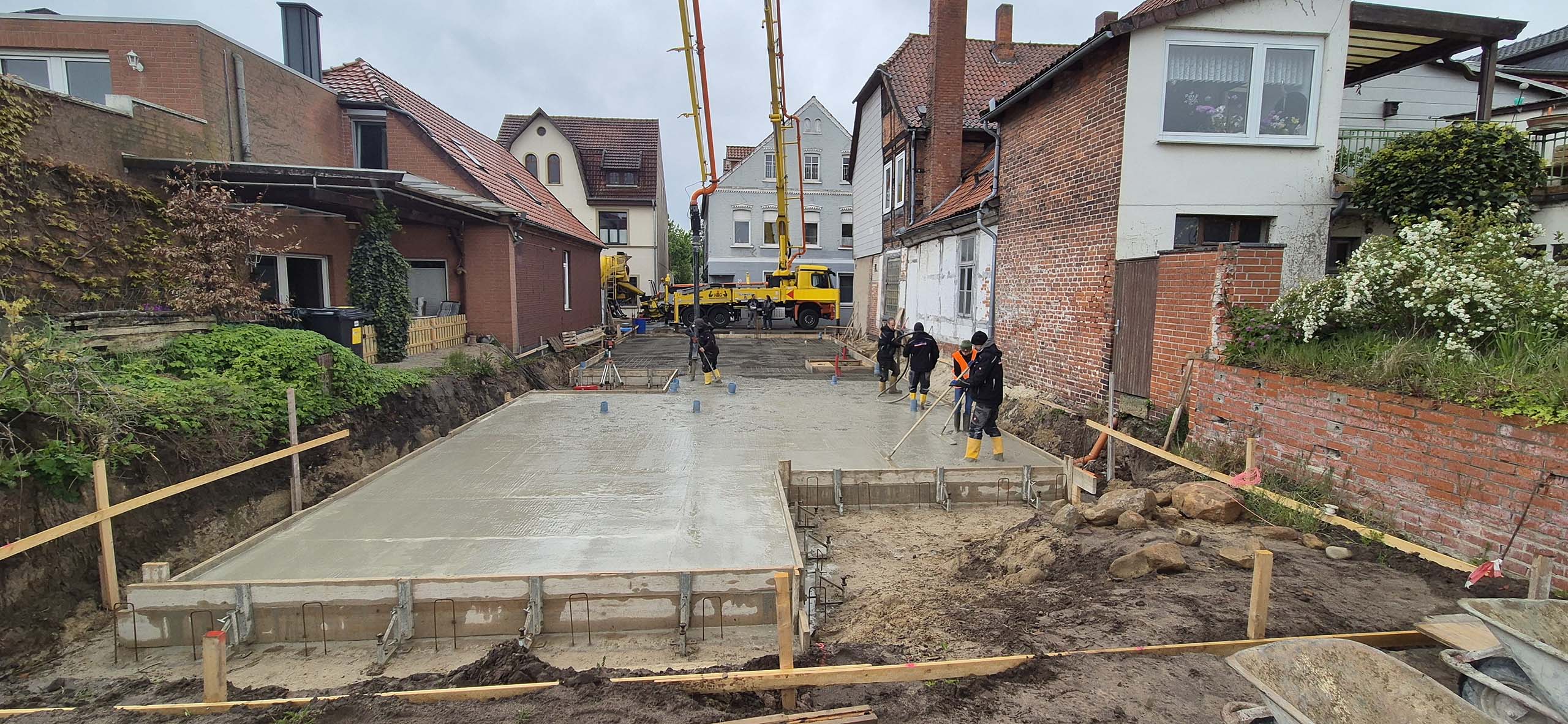 Bauprojekt in Hoya. Mehrere Bauarbeiter begradigen den Beton des frisch gegossenen Fundaments.